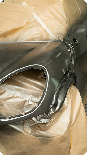 Car body panel masked for painting with brown paper and tape around a round opening.