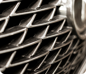 Close-up of a car's front grille with diagonal chrome slats.