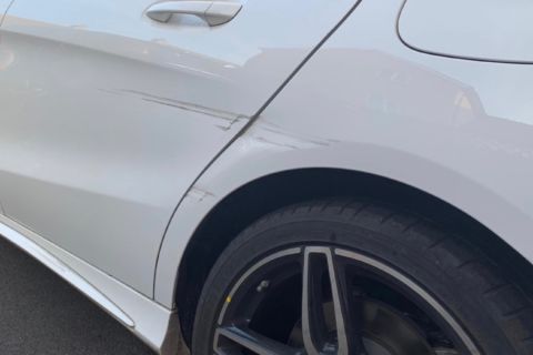 Close-up of a silver car's rear fender and wheel, showing the alloy rim and body panel gap.