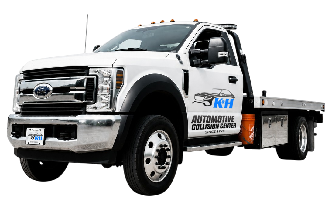 White tow truck with a flatbed, featuring the K&H Automotive Collision Center logo on the door and chrome grille.