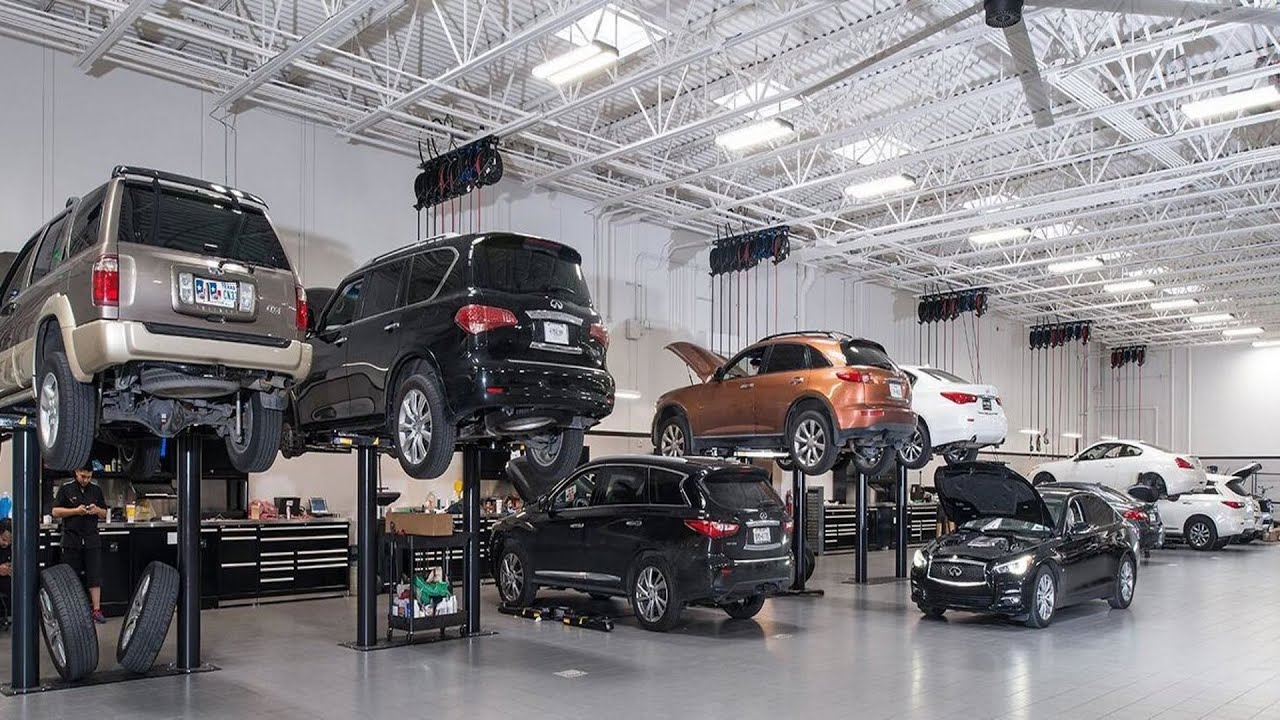 Auto repair shop with multiple SUVs on lifts and a technician working nearby.
